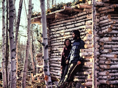 Andi and Heidi in front of their log cabin