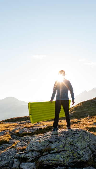 Man in the sun holding a Trekking Ultra sleeping mat in his hands