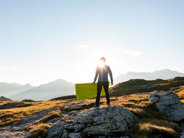 Man in the sun holding a Trekking Ultra sleeping mat in his hands