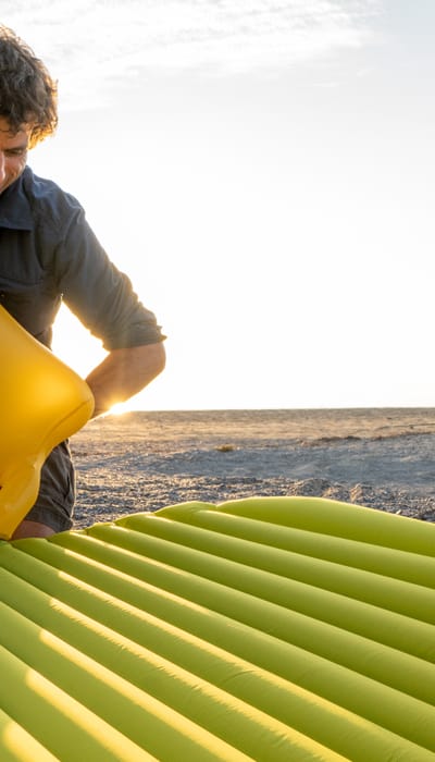 Sleeping mat in a Tent - man with a Schnozzel Pumpbag on the beach